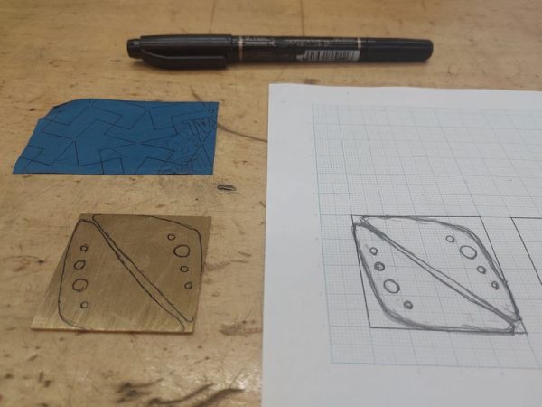 カーボン紙を使って絵をなぞり、真鍮のプレートにデザインの線を写しました。