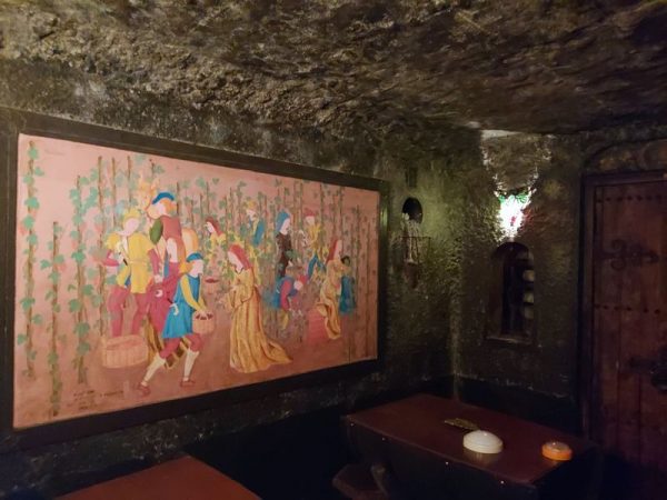 左右の壁には、中世のワイン収穫と製造の壁画が飾られています。壁の岩肌は、高丸氏が根気強く壁に窪みをつけてできたものです。