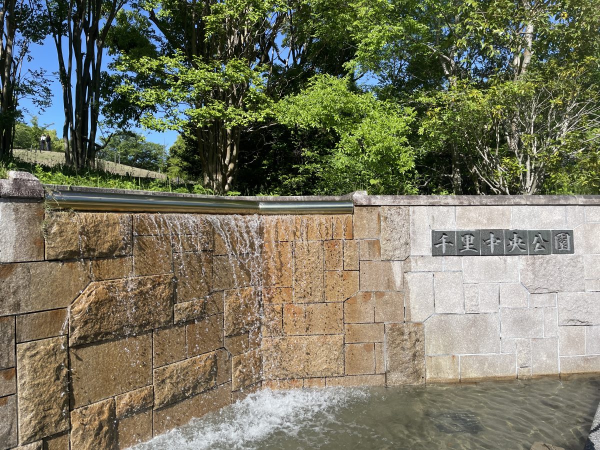 桜の丘の入り口の公園看板の横の水流
