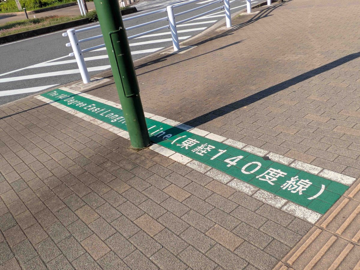路面に書かれた東経140度線の文字。