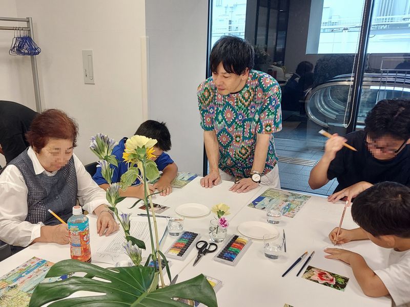 およそ20名の参加者が生花や花の写真を見ながら、本気で描いています。