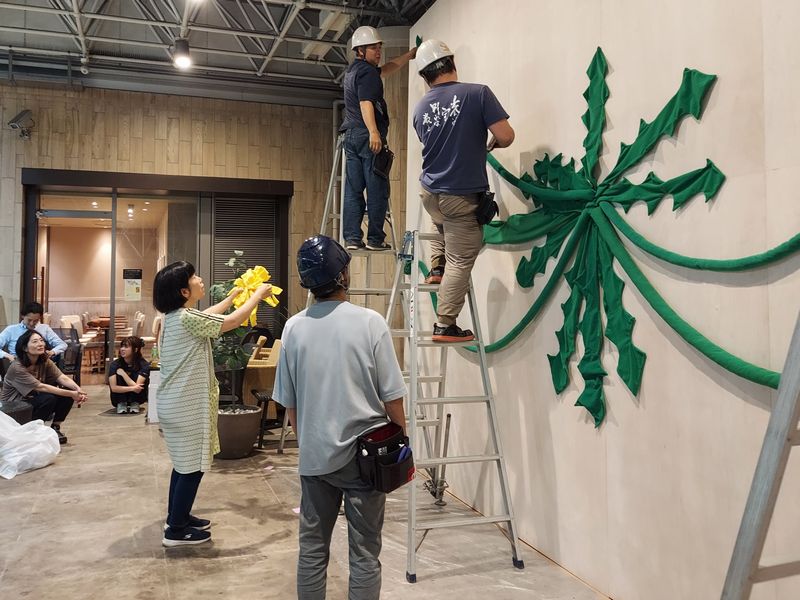 花を大切に手に携えて、指示しながら作業者に渡していく川上さん。アートラインかしわメンバーも見守ります。