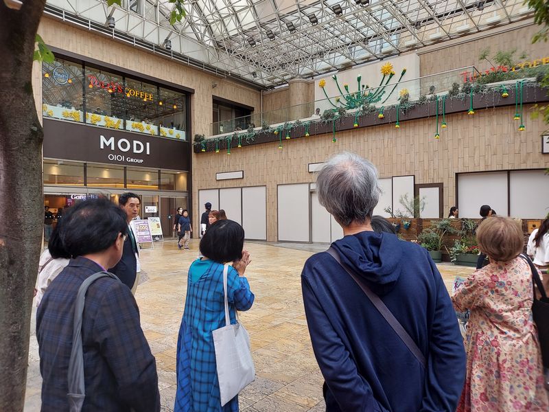 「テラスから垂れ下がっているタンポポは倒れている様子を表現しています」とツアー参加者に説明する川上さん。