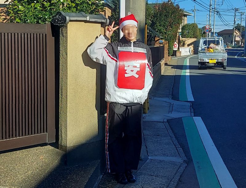 「安」。通りの反対側でも生徒さんが旗を振っています。