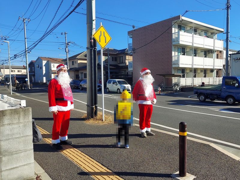 戸張街道の入口では2人のサンタが下校する児童をお出迎え。少年は戸惑いながらも何が書いてあるのか気にしている様子。