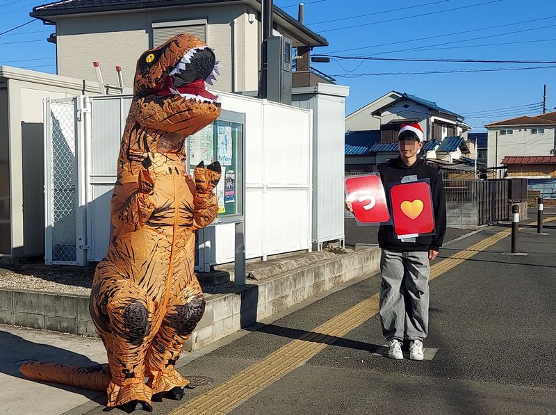 「う」。終点の戸張ふるさと会館の前では、恐竜がお出迎えということで小学生たちも大はしゃぎ! 「ふだん小さなお子さんと触れ合い機会がないので楽しい」と恐竜に扮する学生さん。