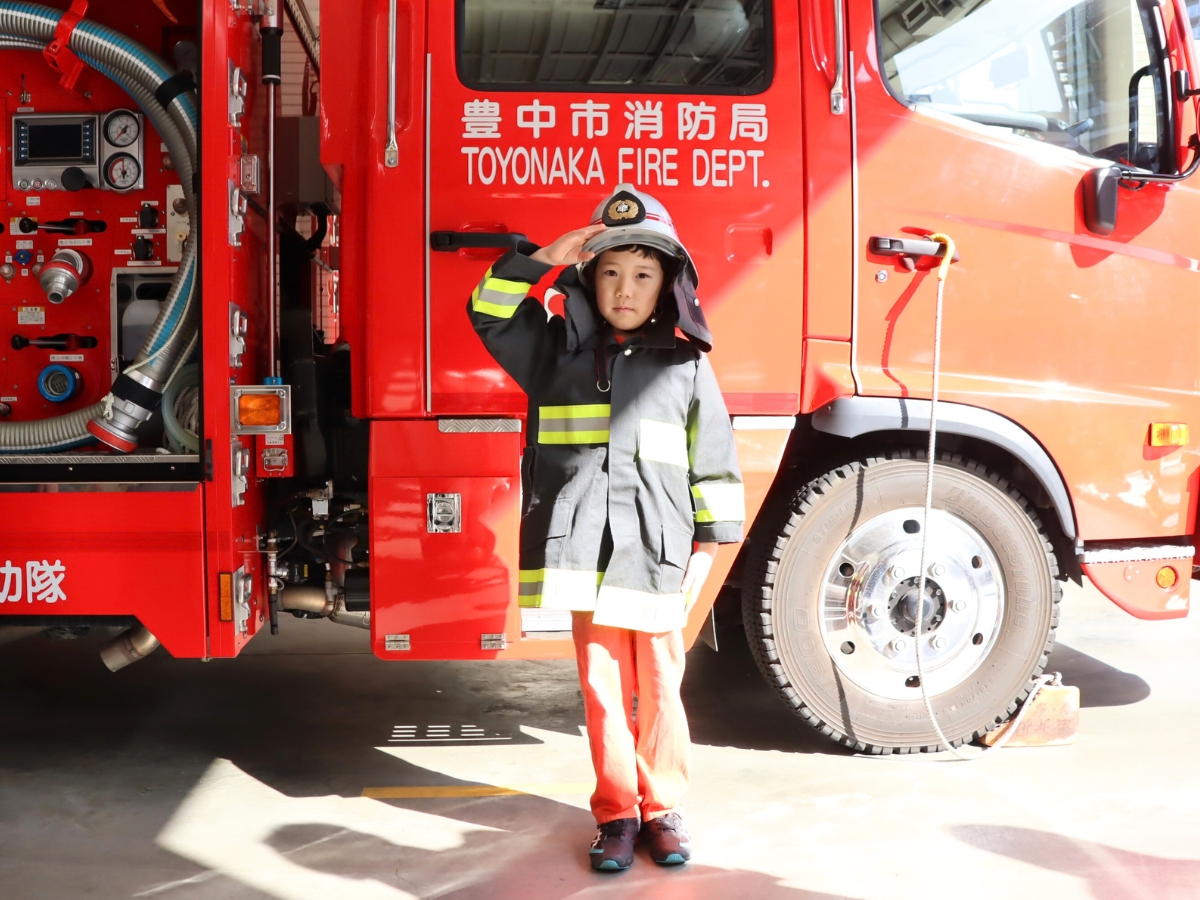 消防服を着て、消防車の前で敬礼！気分はすっかり消防士です。