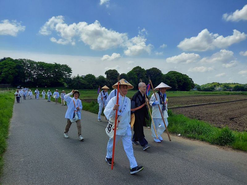 田んぼに囲まれた道を軽快に進む「送り大師」参加者たち。