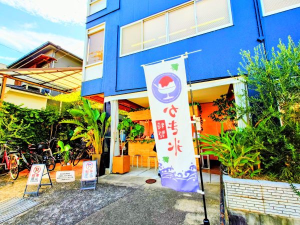 お店の外観、青い建物とかき氷ののぼりが目立ちます