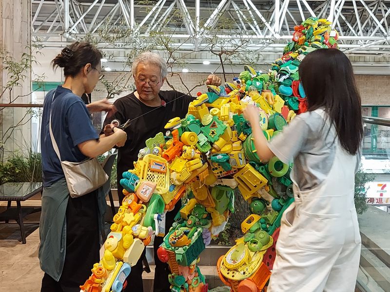 アートラインかしわのメンバーとともに、柏モディ2階テラスにトイザウルスを設置する藤さん。